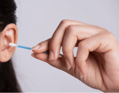 una ragazza sta per pulirsi le orecchie con un cotton fioc, procedura che è da evitare